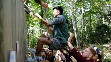 Members of the class of 2023 work together to overcome an obstacle during orientation activities at Brown Center
